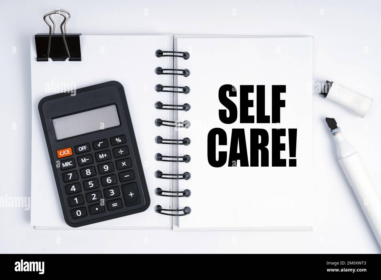 Economia e finanza. Sulla tabella sono riportati un marcatore, una calcolatrice e un notebook con la scritta Self Care Foto Stock