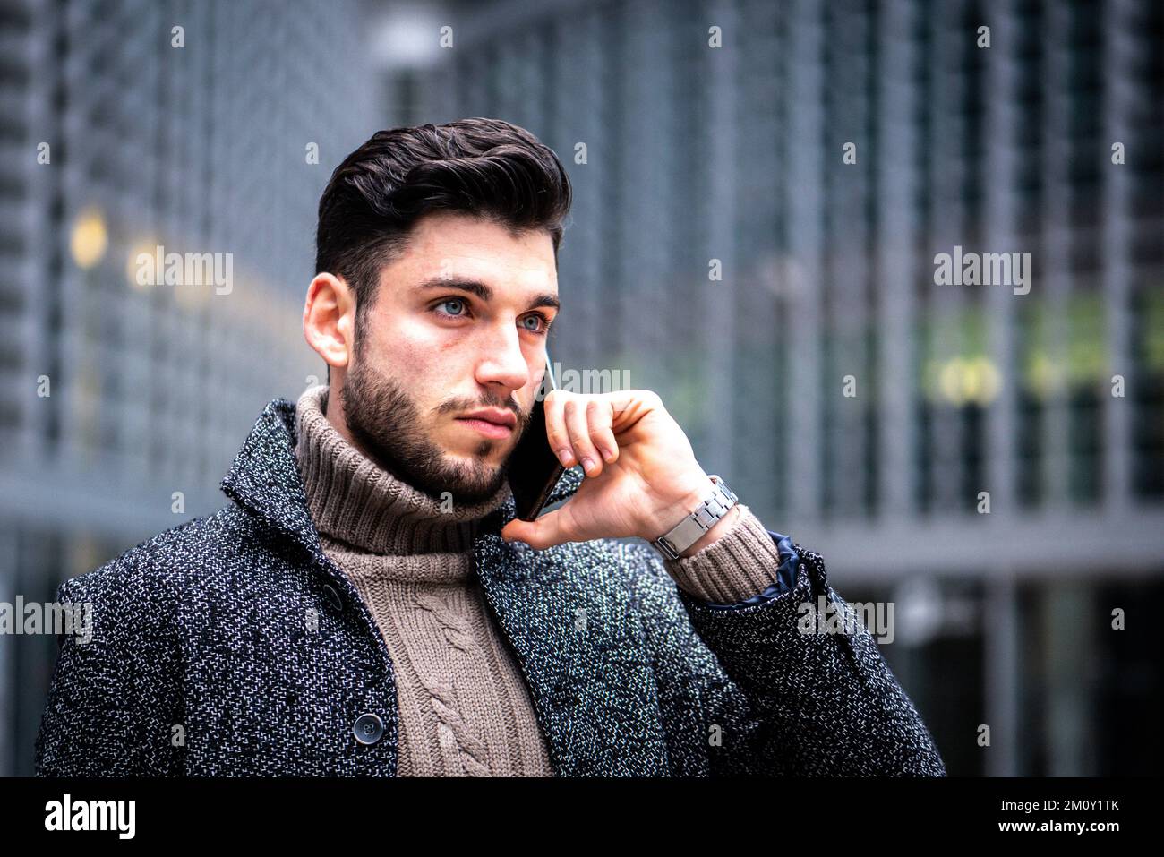 ritratto di un giovane uomo dall'aspetto intenso, moderno uomo d'affari che utilizza smartphone per il lavoro, modello maschile con occhi blu, capelli scuri e barba corta, co Foto Stock