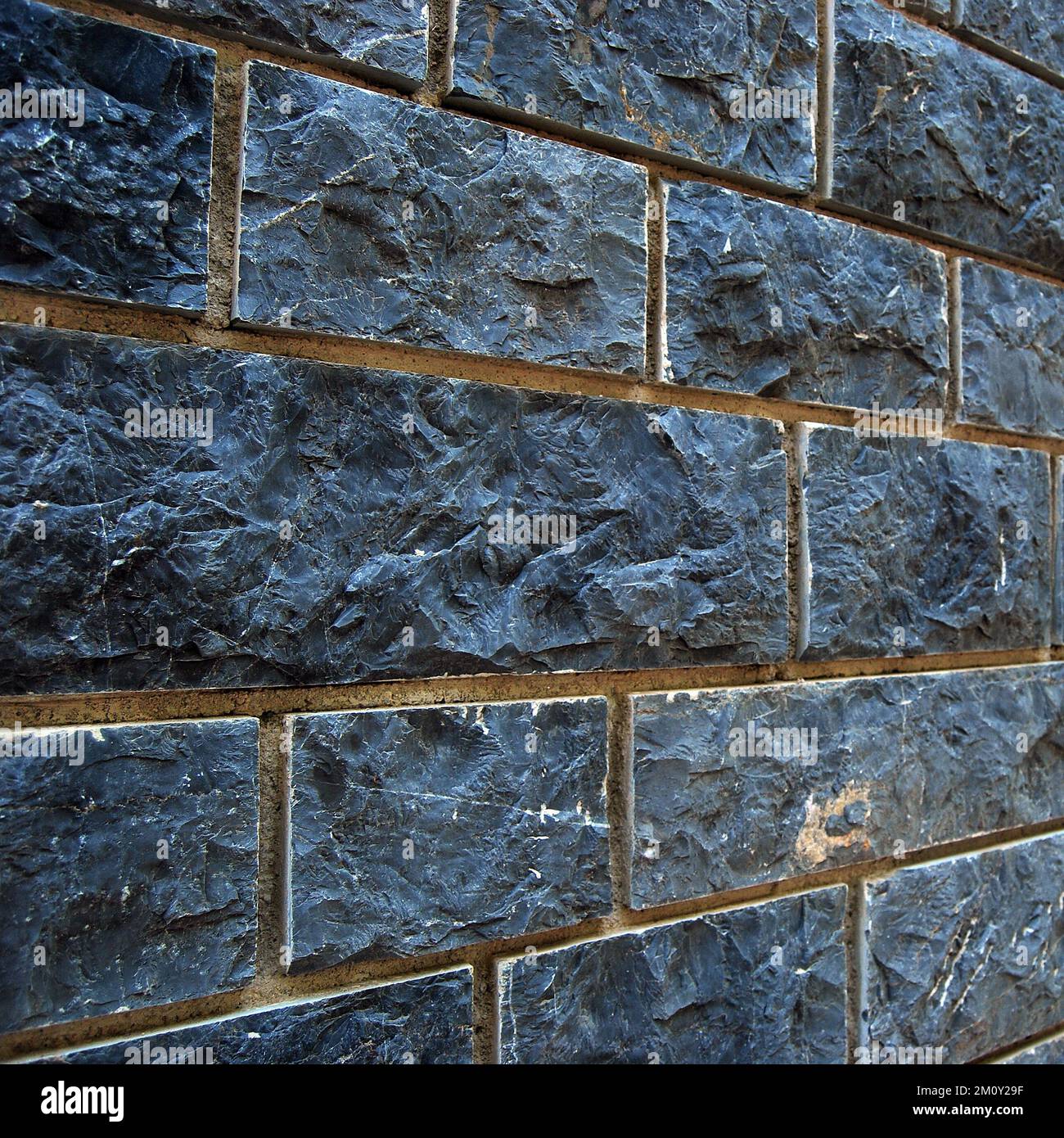 Robusto muro di pietra blu e grigio, adatto per sfondi, allineato senza cuciture Foto Stock