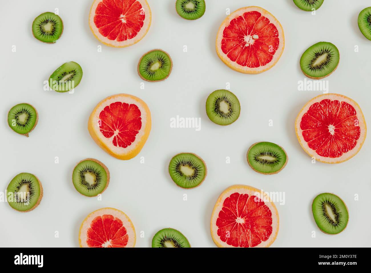 Fettine fruttate di kiwi e pompelmo su fondo bianco. Vista dall'alto. Stile minimalista e colorato Foto Stock