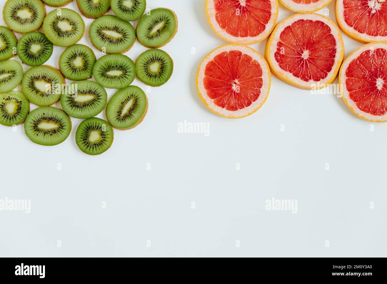 Mix di frutta di kiwi e fette di pompelmo su sfondo bianco. Vista dall'alto. Stile minimalista e colorato. Spazio di copia Foto Stock