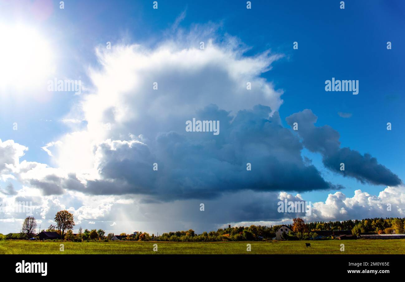 Grandi nuvole sul lato del sole, con una fascia di pioggia. Foto Stock