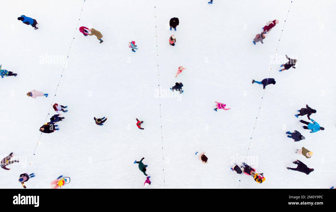 Persone che pattinare su una pista di pattinaggio su ghiaccio all'aperto. Vista dall'alto. Molta gente che pattinando sul ghiaccio della pista. Vista aerea del drone. Bella Skating Sport e attività invernali all'aperto sfondo Foto Stock