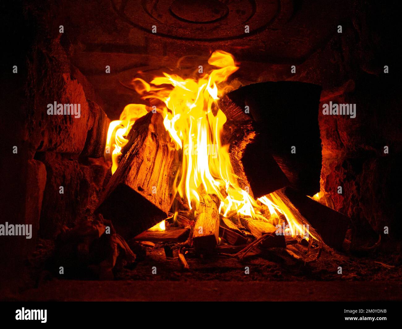 legno aranciato in un forno in pietra all'interno, fuoco nel camino. Foto Stock