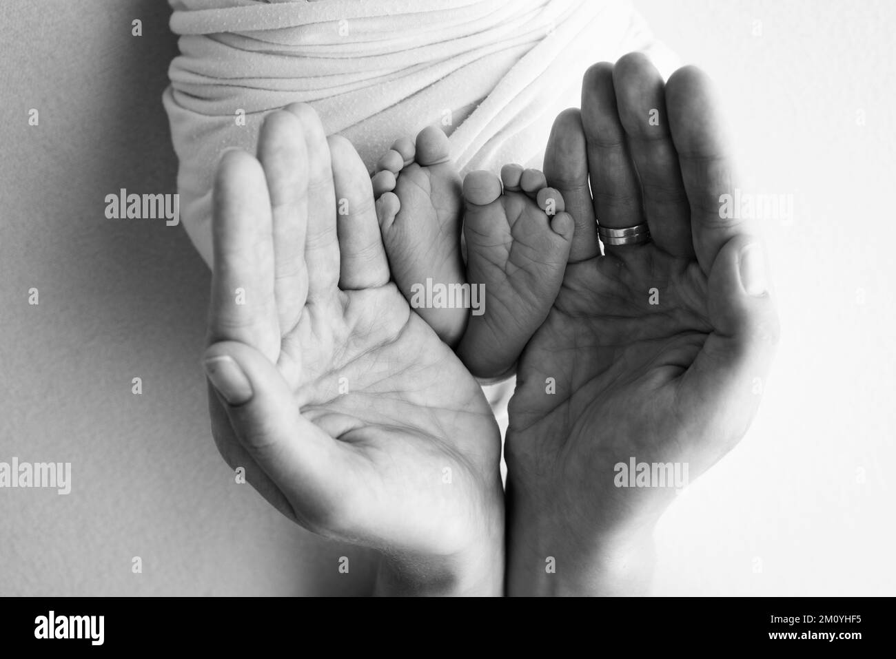 Gambe, dita dei piedi, piedi e talloni di un neonato. Con le mani dei genitori, padre, madre tiene delicatamente le gambe del bambino. Foto Stock