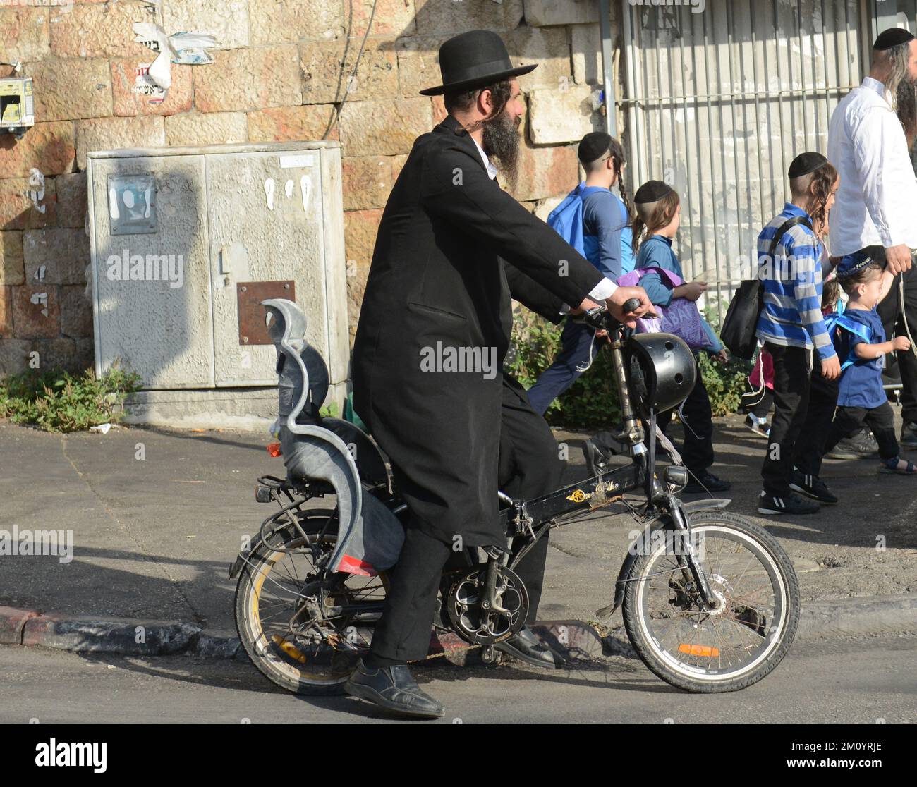 Un ebreo Haredi in bicicletta nel quartiere di Mea Shearim a Jerealem, Israele. Foto Stock