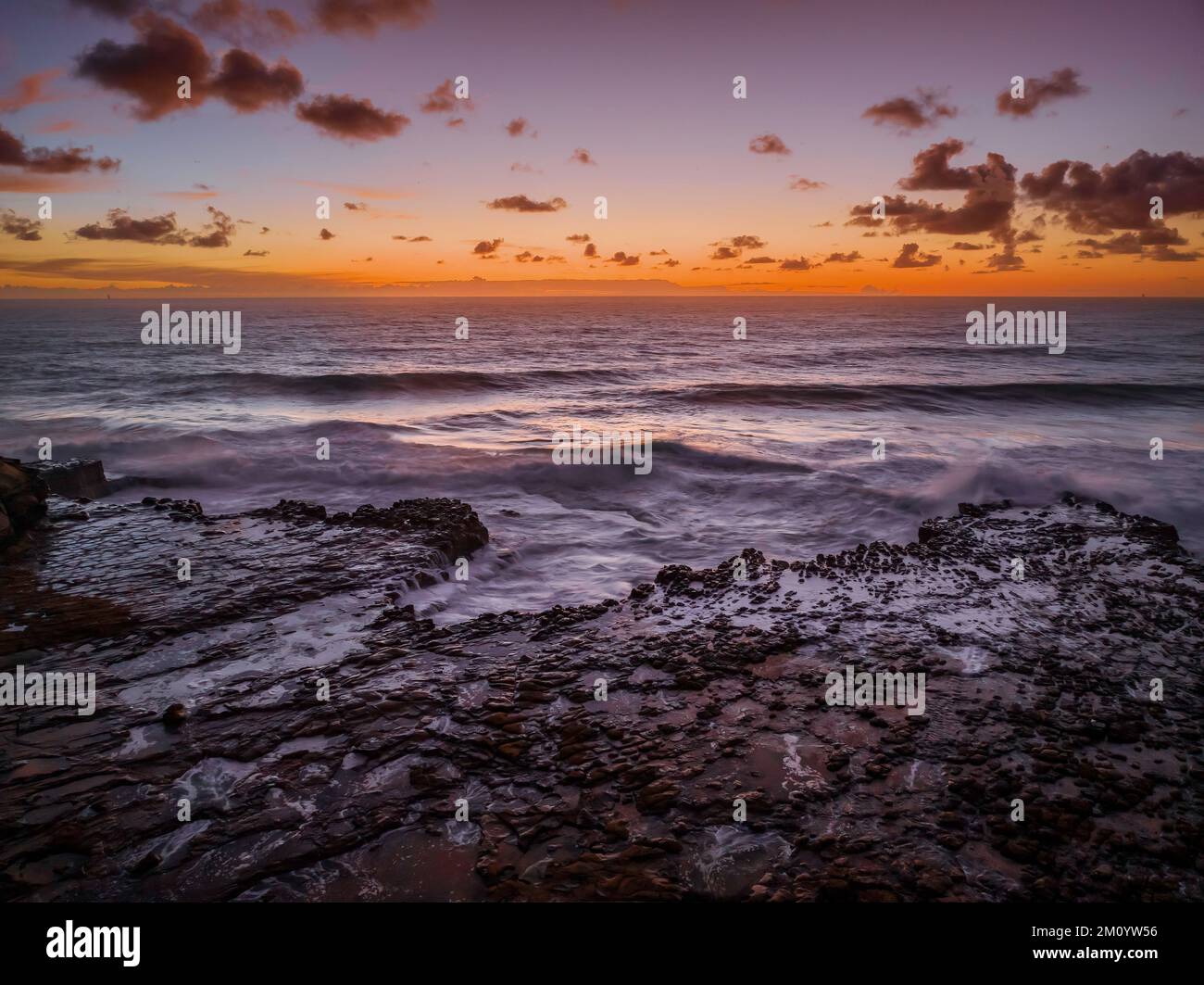 Dawn Seascape con nuvole, piattaforma rocciosa, onde di buone dimensioni e molta atmosfera a North Avoca Beach sulla costa centrale, NSW, Australia. Foto Stock