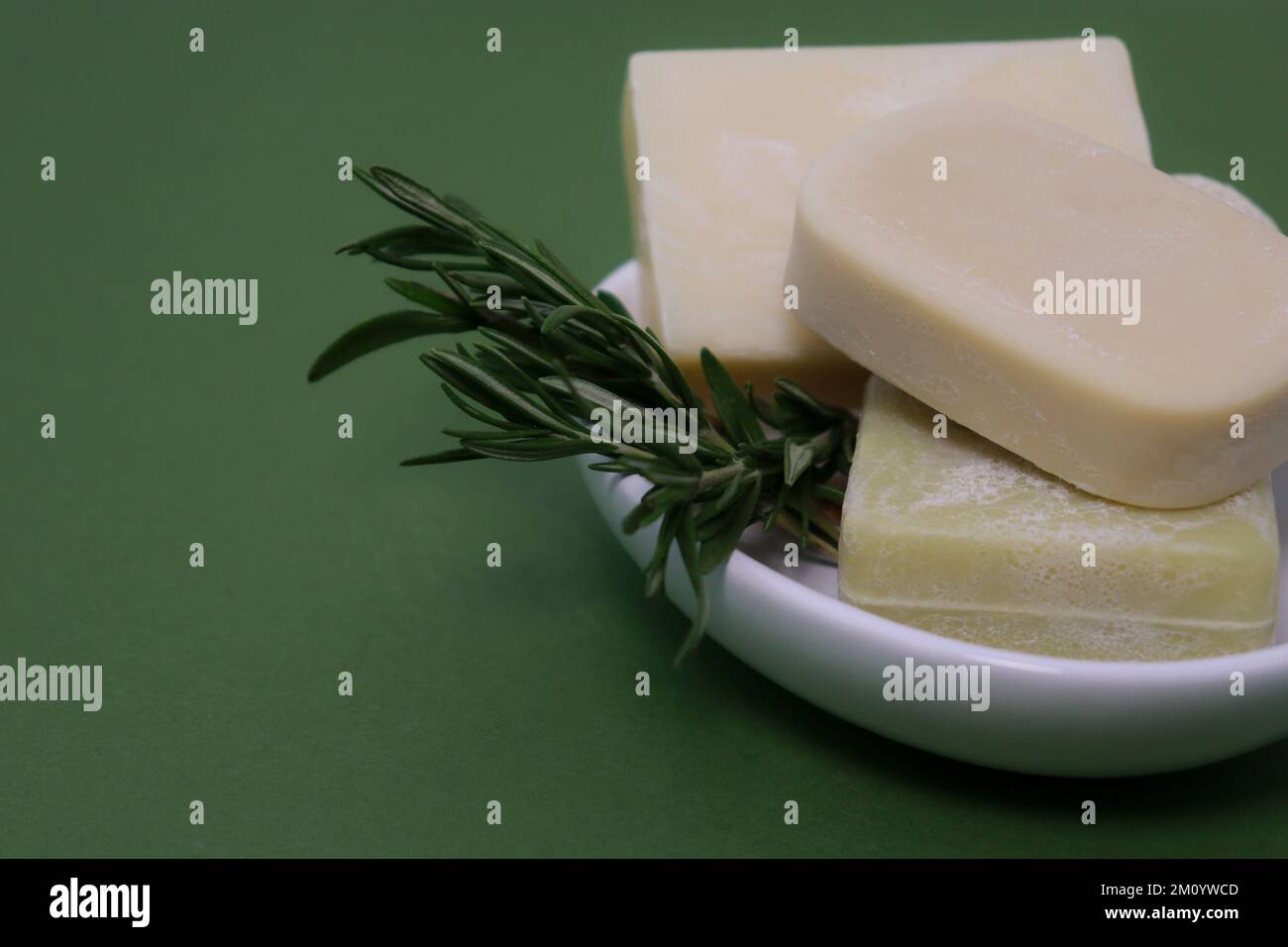 primo piano delle saponette fatte a mano su un vassoio per sapone bianco, fondo verde Foto Stock