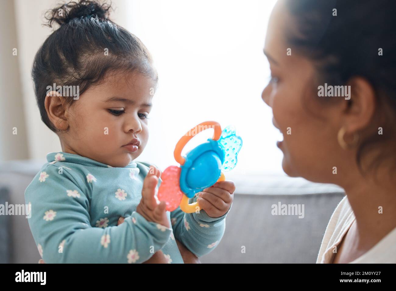 Rimanere intrattenuto mentre mamma fa la conversazione. una ragazza adorabile che gioca con un giocattolo mentre si lega con la madre. Foto Stock