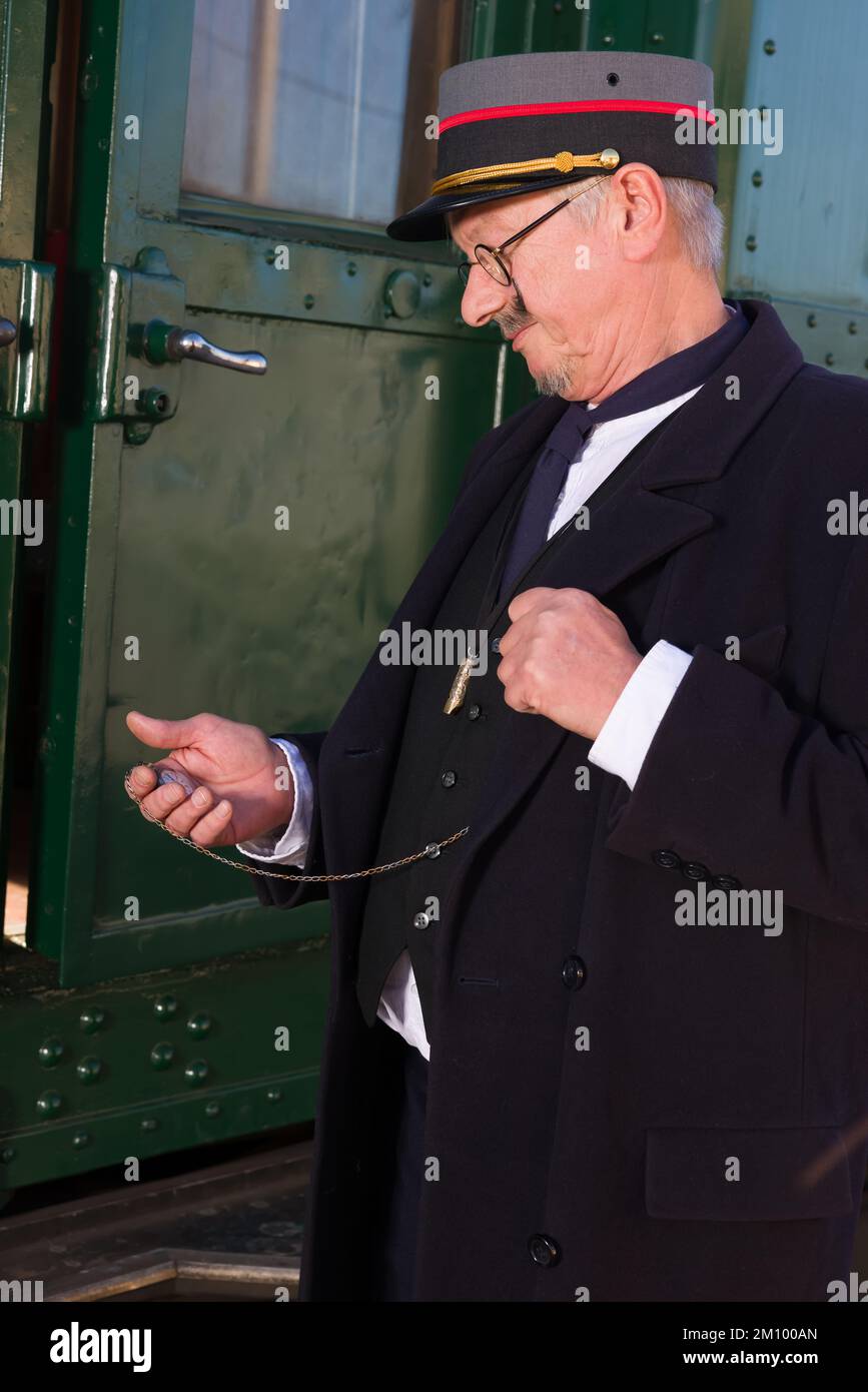 Scena di rievocazione di un conduttore ferroviario d'epoca alla partenza della carrozza ferroviaria di prima classe Foto Stock Scena di rievocazione di un conduttore ferroviario d'epoca alla partenza della carrozza ferroviaria di prima classe Foto Stock