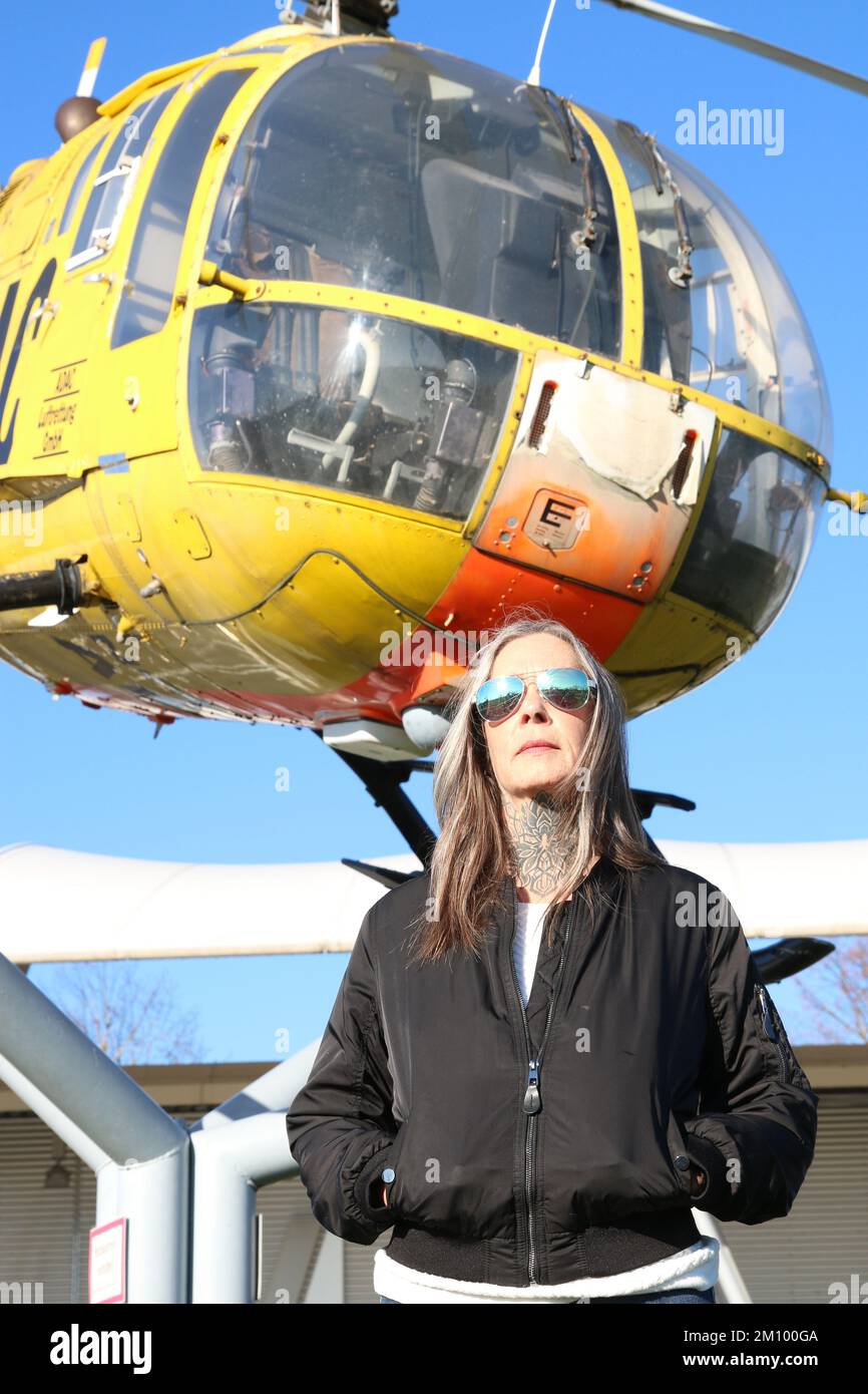 Miglior modello femminile Ager con occhiali da sole di fronte a un elicottero invecchiamento migliore. Frau im besten Alter vor einem Helikopter mit Sonnenbrille und Jacke. Foto Stock