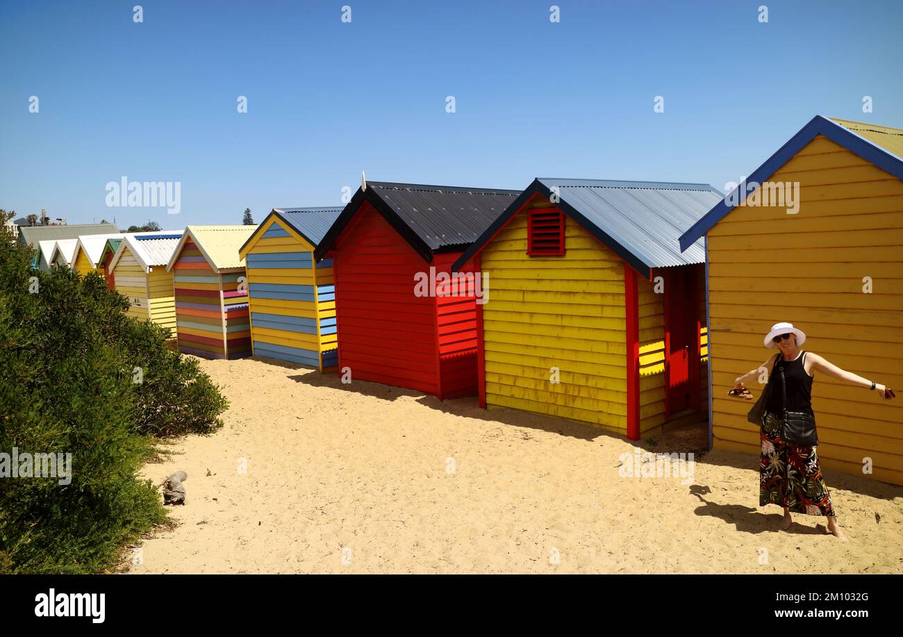 Donna felice di fronte ai colorati box spiaggia a Brighton Beach Melbourne Foto Stock