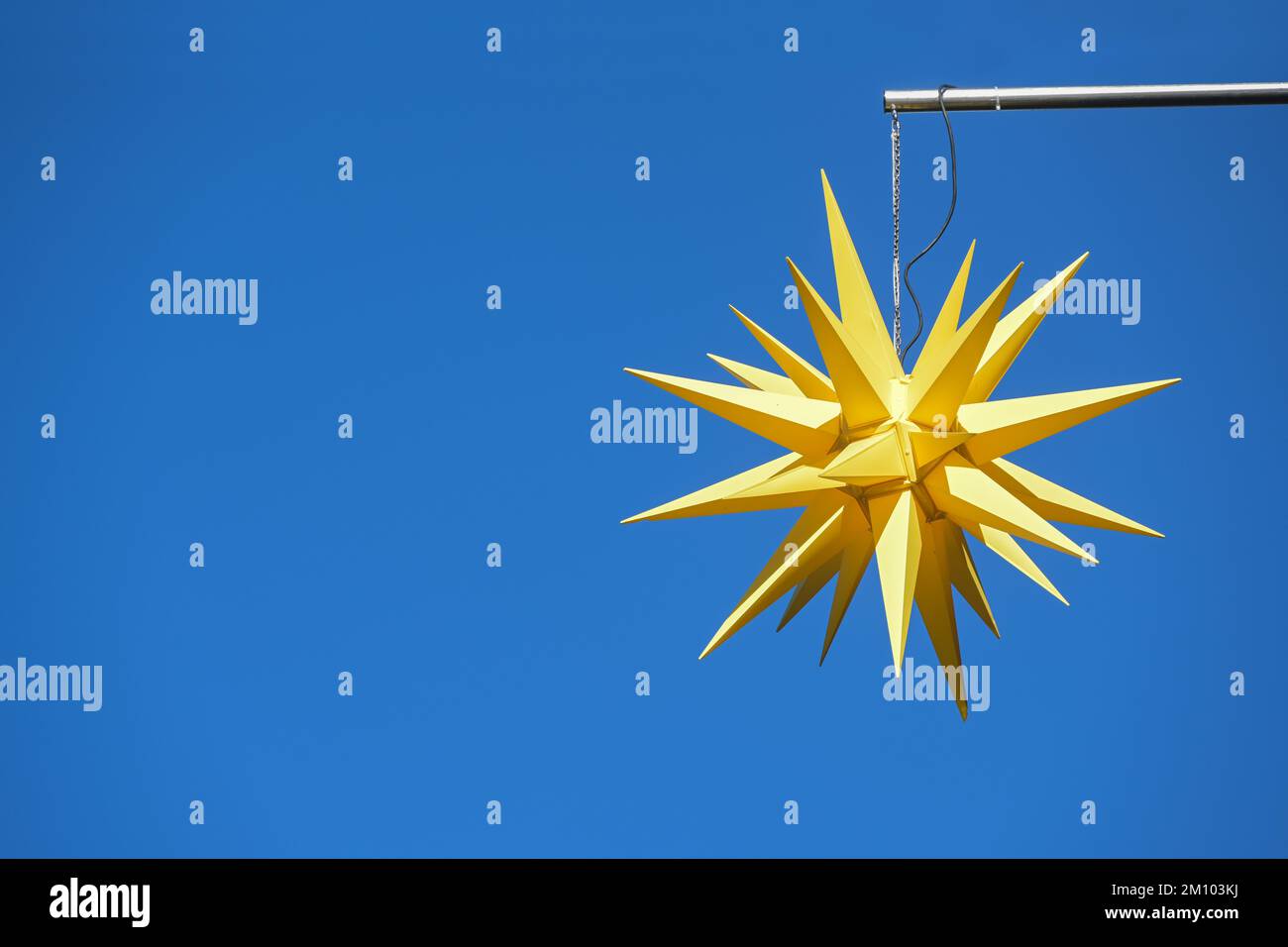 Stella Morava gialla sospesa contro il cielo azzurro, decorazioni tradizionali all'aperto e simbolo religioso per l'Avvento, il Natale e l'Epifania, copia Foto Stock