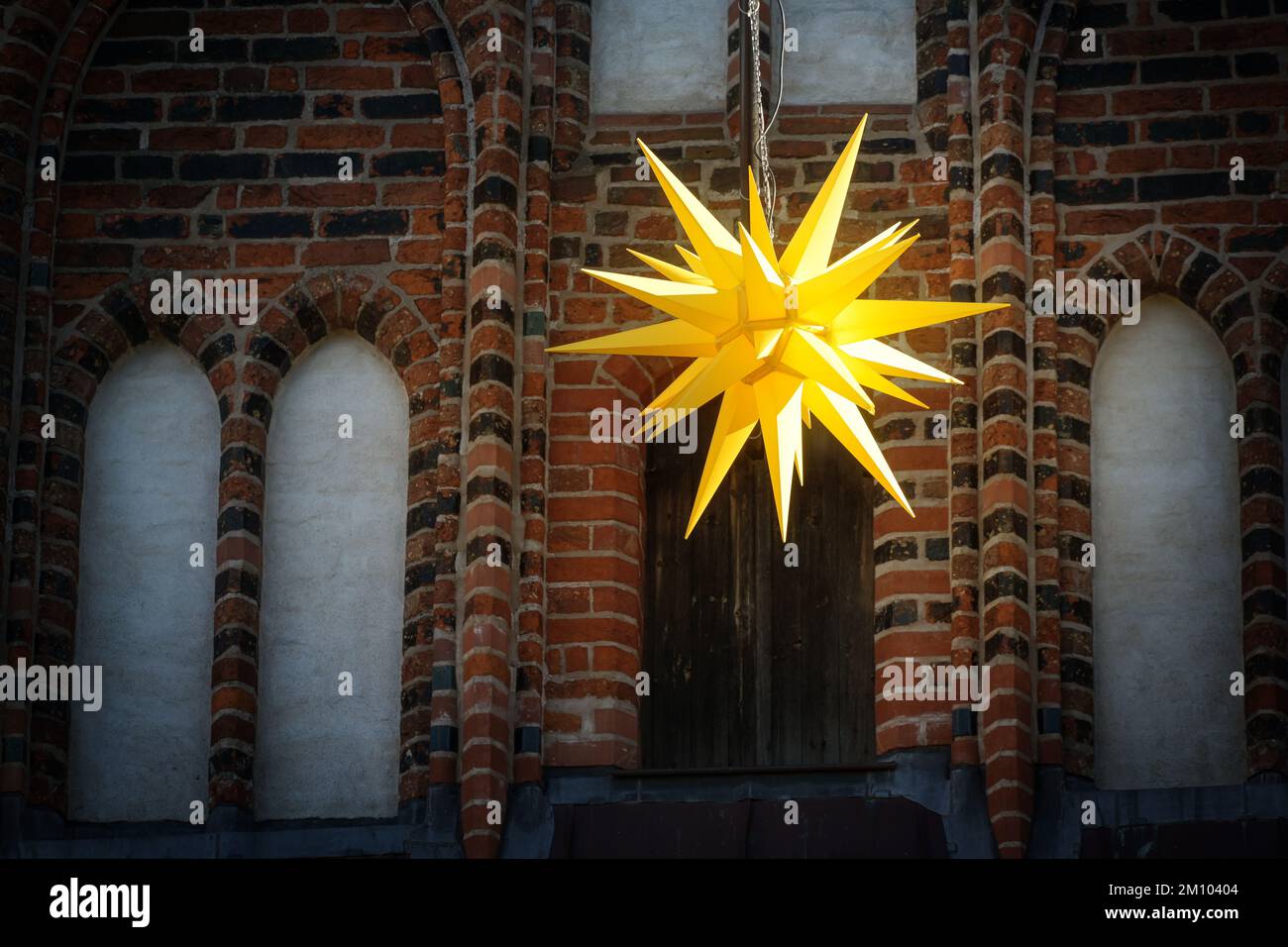 Stella gialla della Moravia che si trova di fronte a un edificio storico di Lubecca, in Germania, con decorazioni tradizionali per l'Avvento, il Natale e l'Epifania, Foto Stock