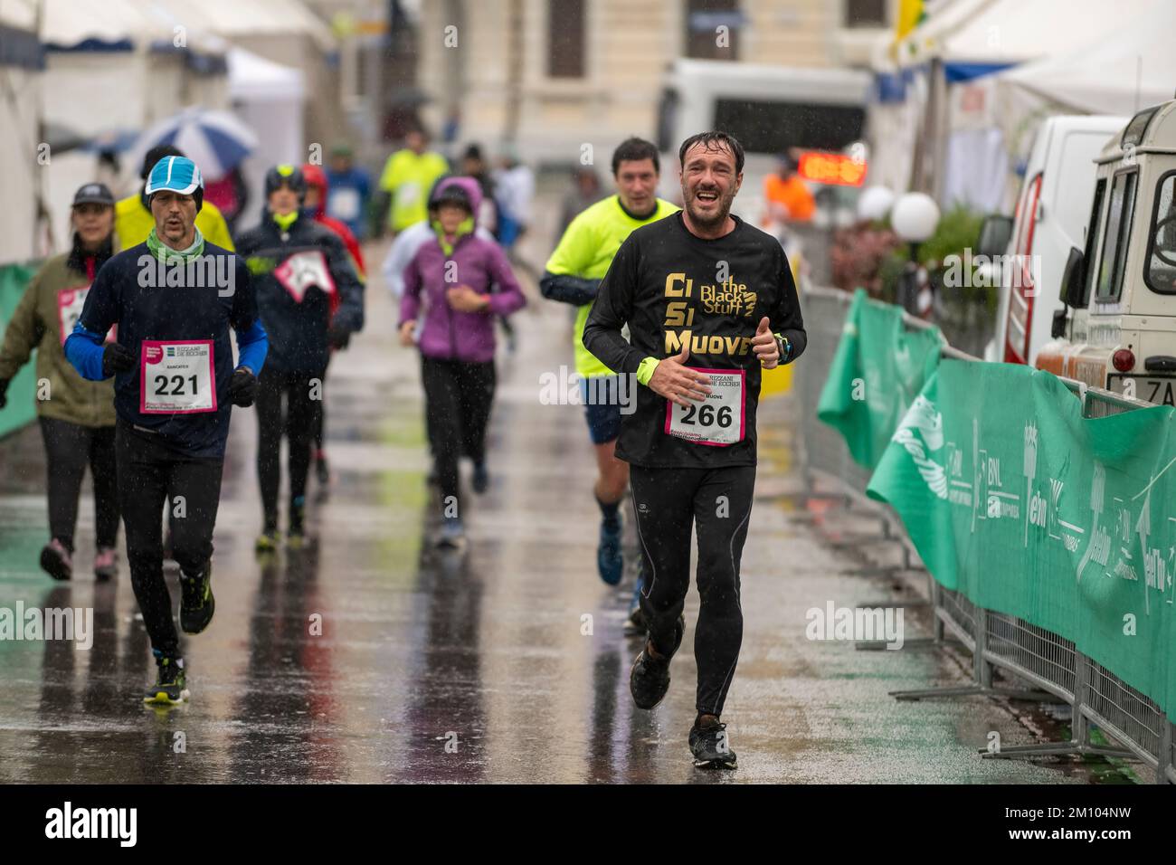 Atleti che corrono sotto la pioggia in occasione della gara di staffetta della maratona Telethon. Città di Udine, Italia. Dicembre 4, 2022. Foto Stock