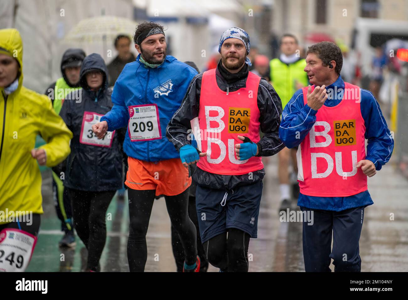 Atleti che corrono sotto la pioggia in occasione della gara di staffetta della maratona Telethon. Città di Udine, Italia. Dicembre 4, 2022. Foto Stock