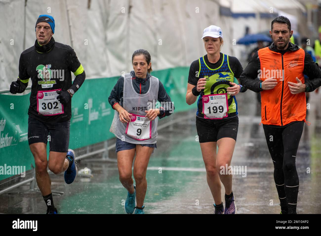 Atleti che corrono sotto la pioggia in occasione della gara di staffetta della maratona Telethon. Città di Udine, Italia. Dicembre 4, 2022. Foto Stock