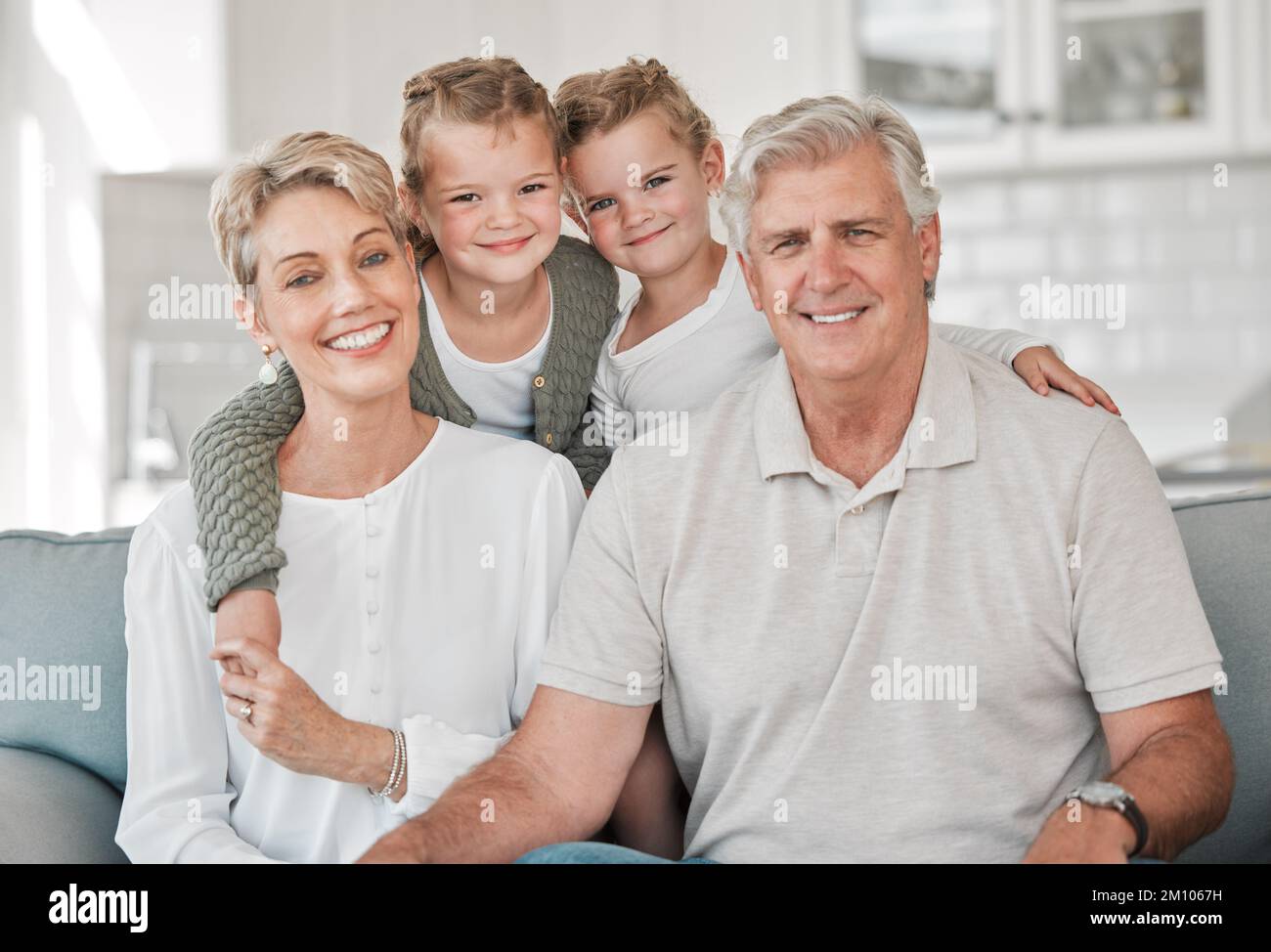 I nonni sono un tesoro nella famiglia. una coppia felice e le loro nipoti si rilassano sul divano di casa. Foto Stock