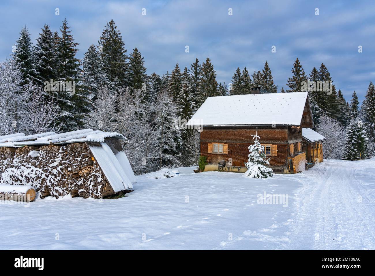 Holzhaus, Ferienhaus am Waldrand auf dem Hügel im ersten Schnee, verschneite Landschaft mit weißen Wiesen und Bäumen. Avent und Weihnachtszeit Ferien Foto Stock