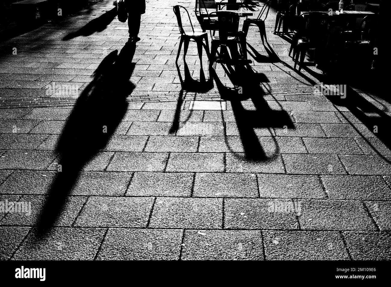 Lunghe ombre di sedie, tavoli e figure in bianco e nero. Retroilluminazione spettacolare con ombre che arrivano direttamente verso la fotocamera.concetto di ombra Foto Stock