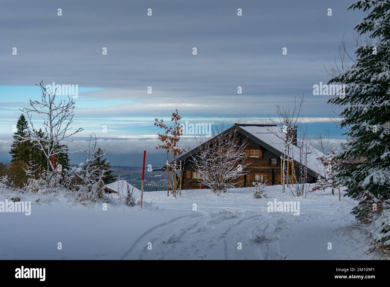 Holzhaus, Ferienhaus am Waldrand auf dem Hügel im ersten Schnee, verschneite Landschaft mit weißen Wiesen und Bäumen. Avent und Weihnachtszeit Ferien Foto Stock