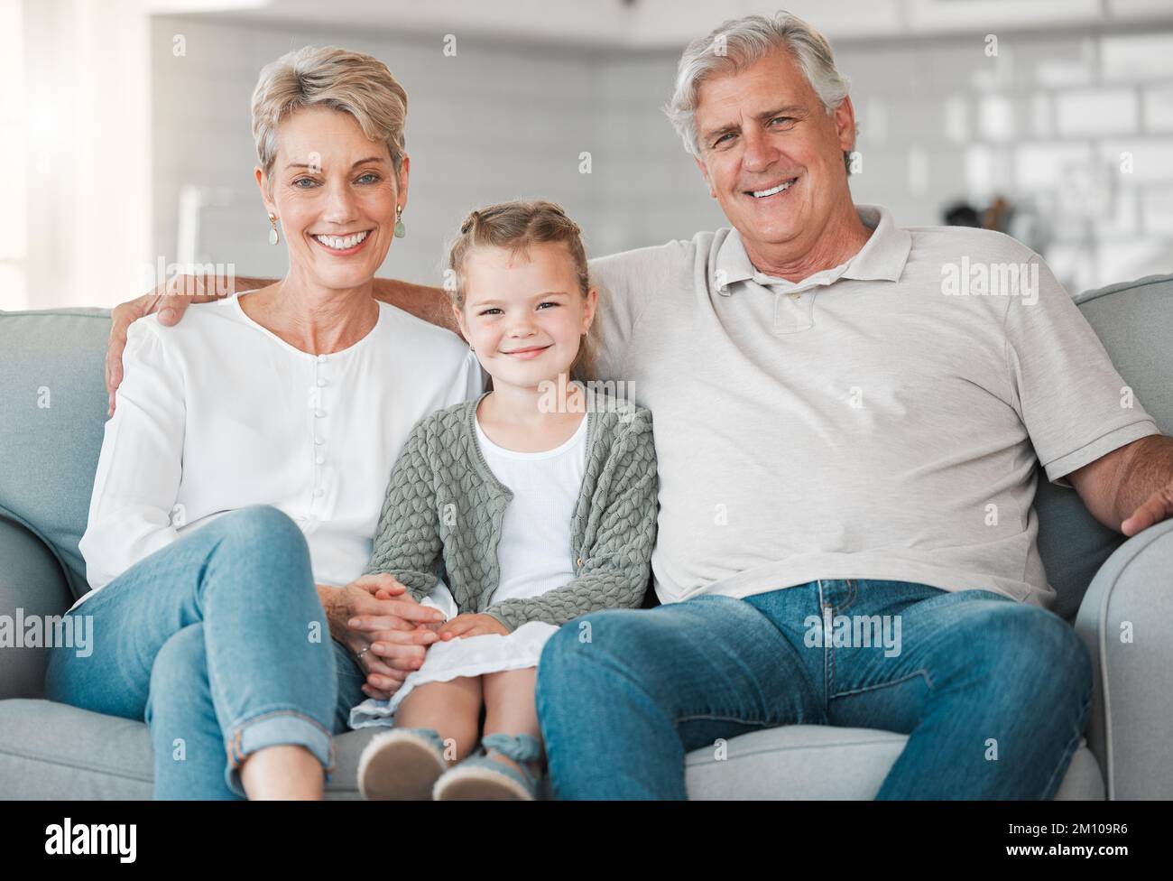 Alcune delle nostre più grandi benedizioni ci chiamano nonna e nonno. una coppia felice e la loro nipote si rilassano sul divano di casa. Foto Stock