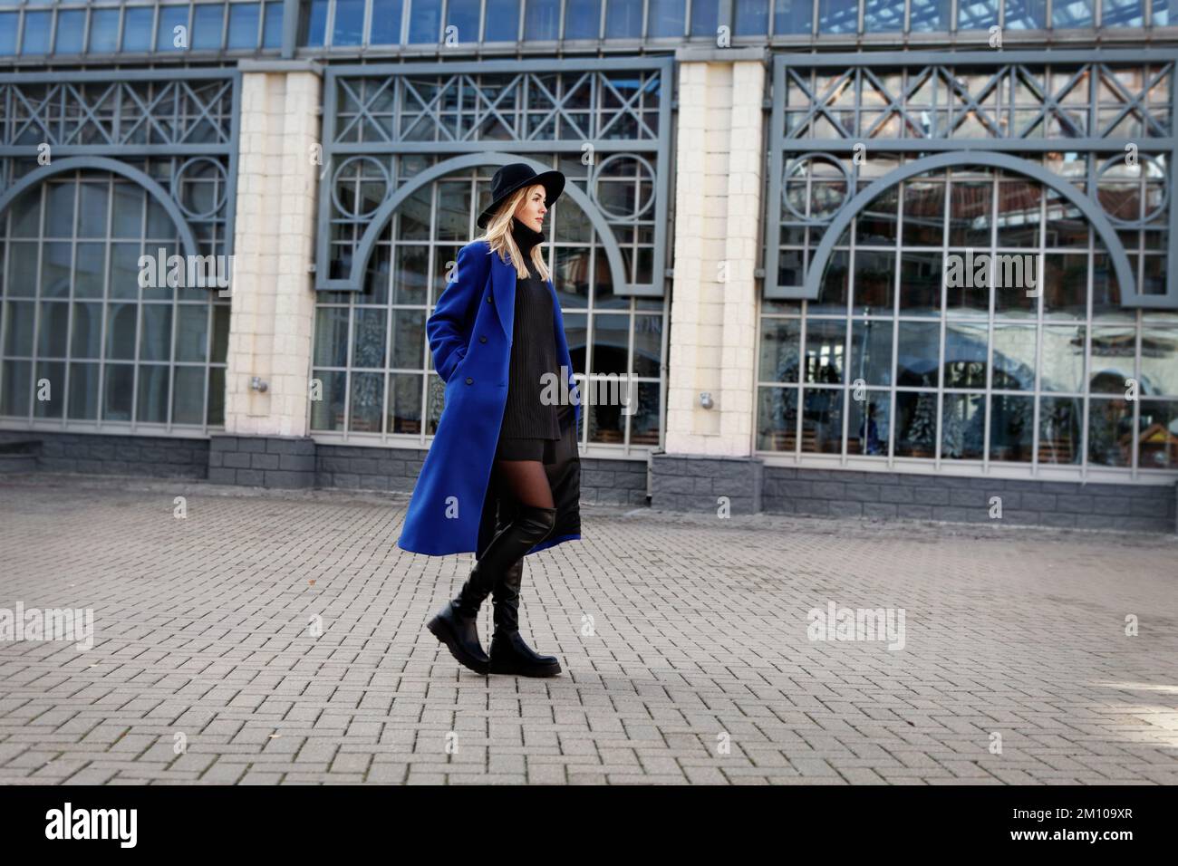 Bella donna alla moda che cammina per strada. Tendenza di tendenza in autunno o primavera abiti è blu cappotto, feltro cappello, pelle nera GAMBALETTO PIATTO Foto Stock
