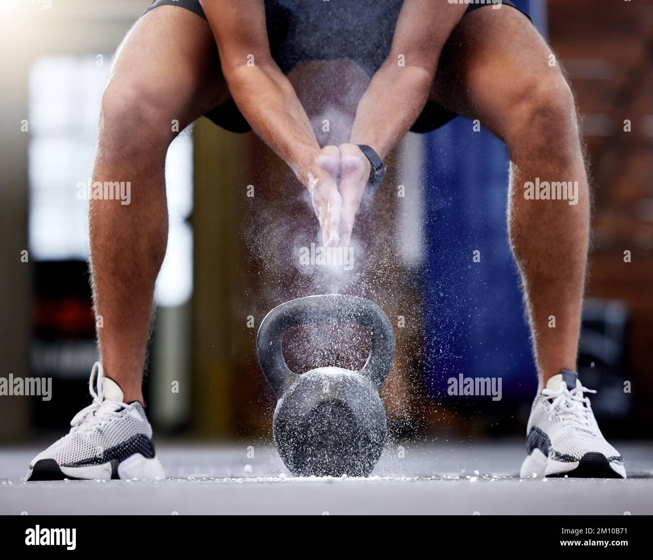 Uomo, kettlebell e mani applappate con polvere preparandosi per l'allenamento in palestra. Sport, fitness o atleta maschile con peso e polvere di gesso per la presa Foto Stock