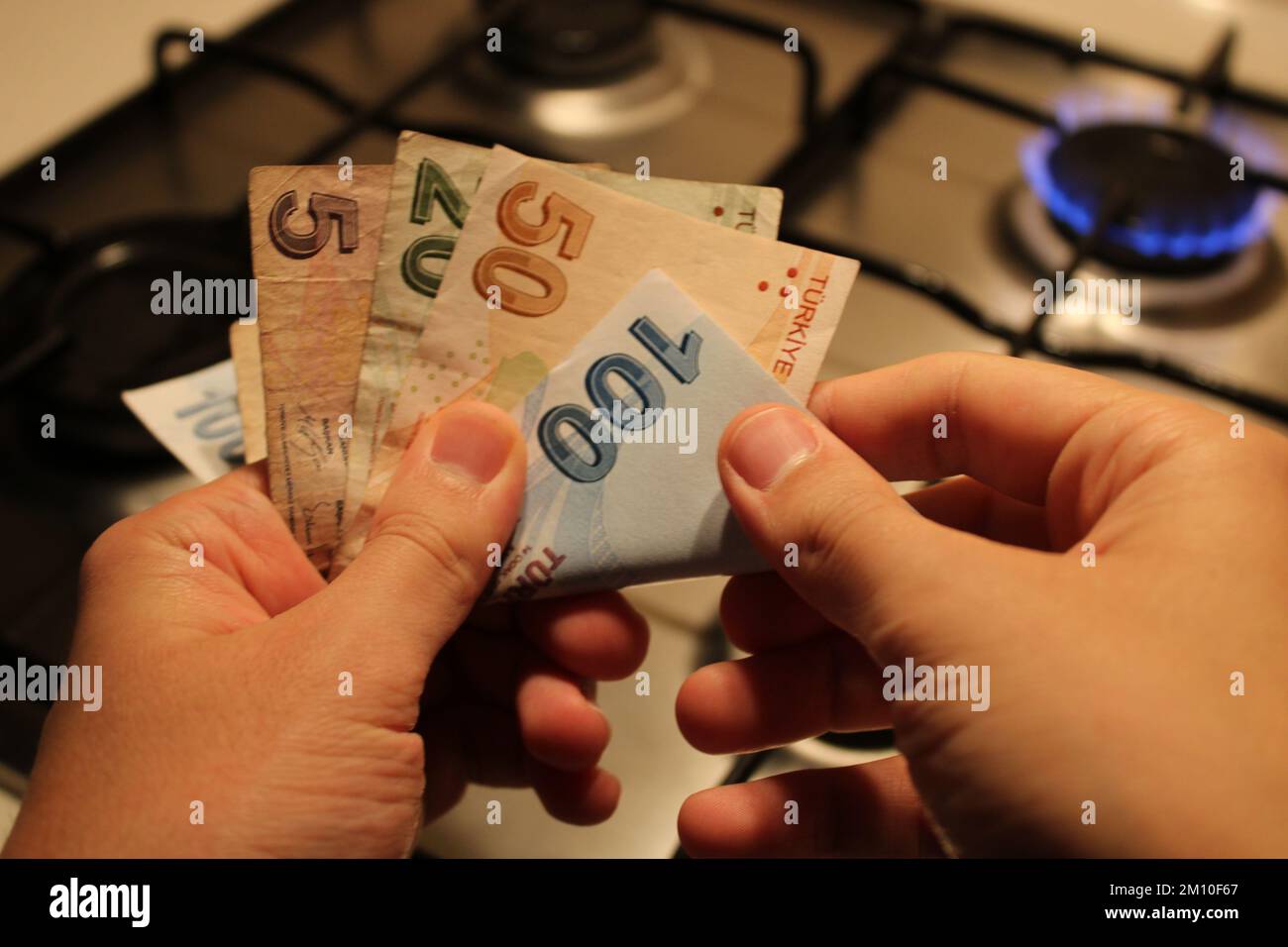 mano uomo che conta soldi. stufa a gas in background. costi elevati del gas e dell'elettricità, crisi economica. Foto Stock