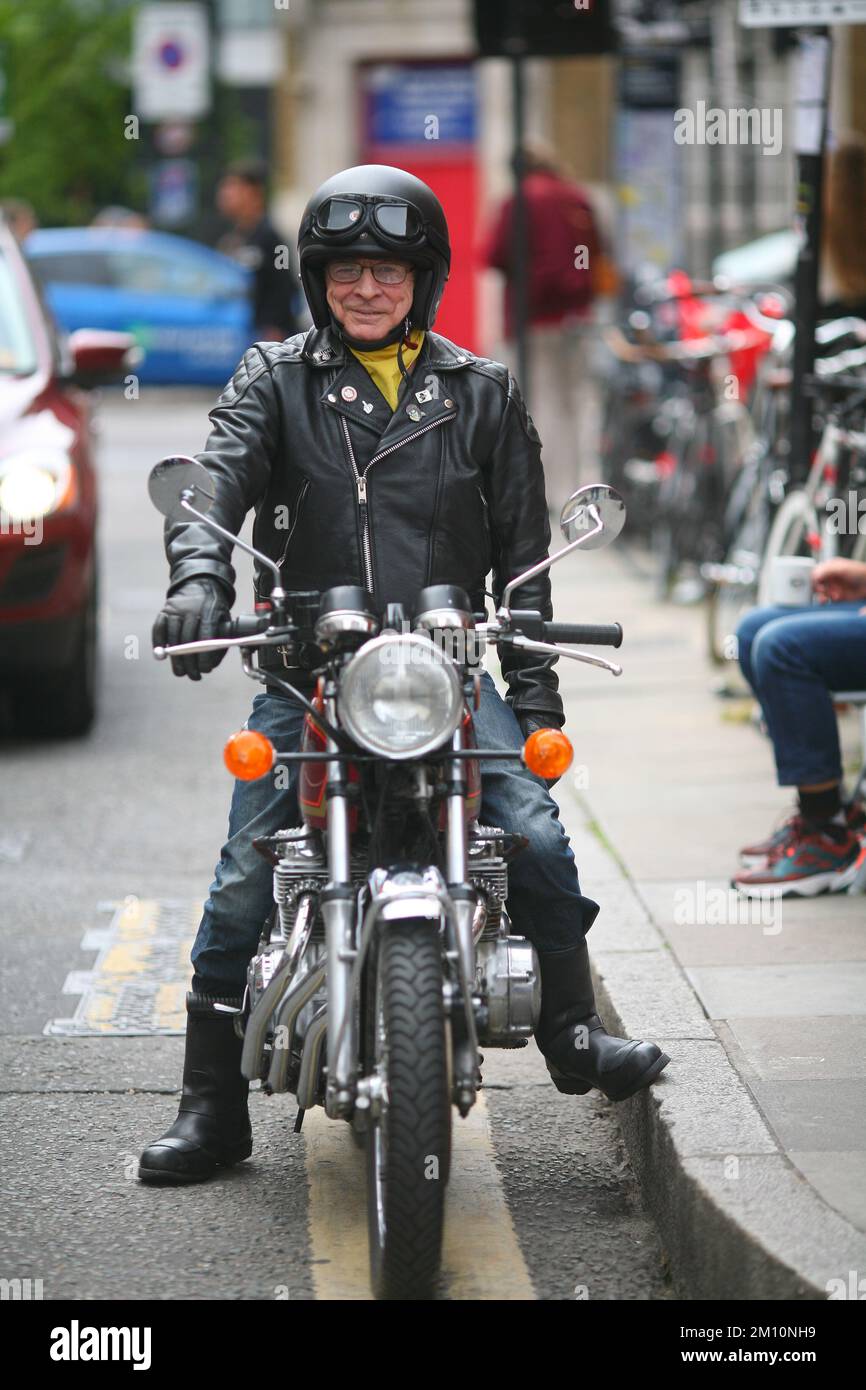Motociclista uomo in moto al largo di Brick Lane a East London, indossando giacca da motociclista classica, jeans e stivali da motociclista Foto Stock