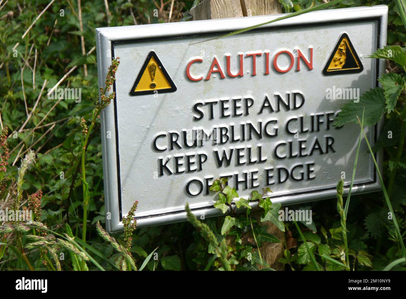 Metal Caution (Warning) Sign on a Wooden Post near Boscastle on the South West Coastal Path in Cornwall, England, UK. Foto Stock