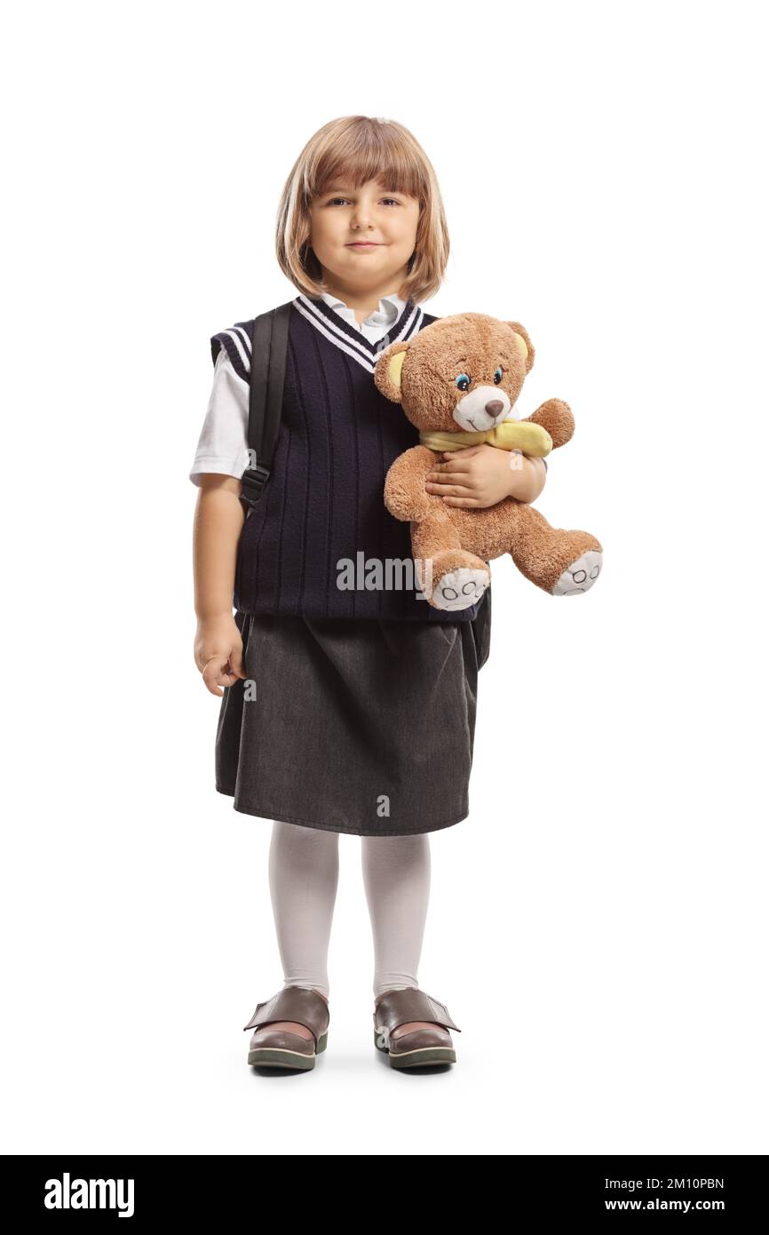 Profilo a tutta lunghezza di una bambina in uniforme che tiene un orsacchiotto isolato su sfondo bianco Foto Stock