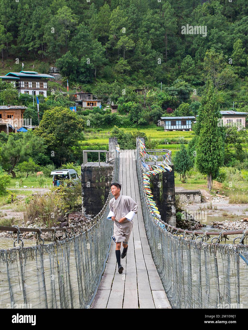 Il giovane monaco attraversa il ponte sospeso vicino al Punakha Bhutan Foto Stock