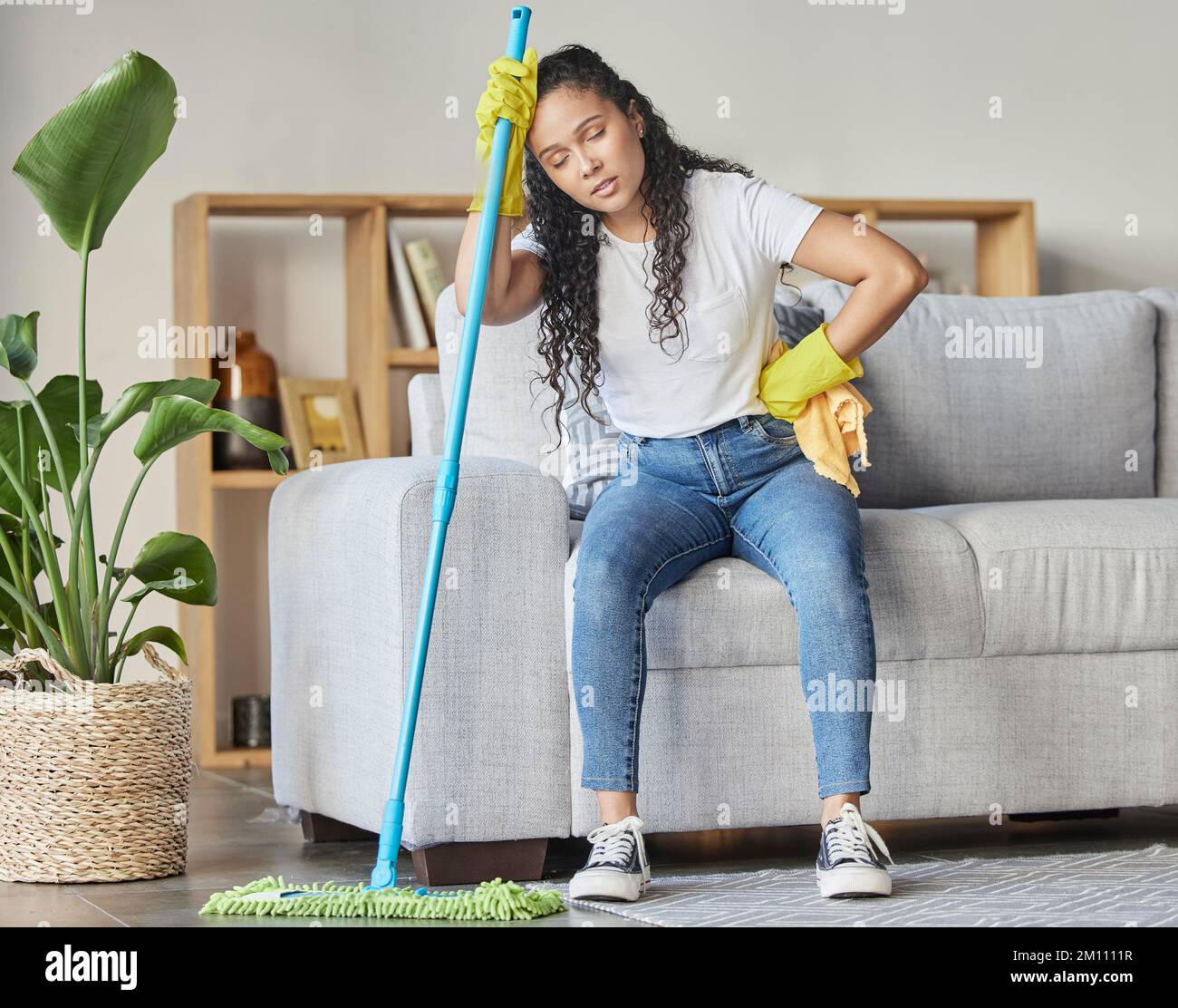 Pulizia, stanco e spazzatura con la donna in soggiorno per pulizia, igiene o disinfezione. Dolore, esausto e fatica con la ragazza più pulita a riposo Foto Stock