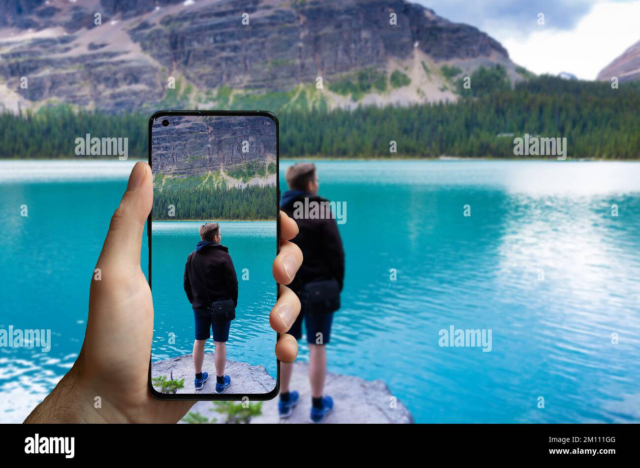 Tourist scattare una foto con un telefono cellulare di un uomo in piedi al lago Ohara, Canada. Foto Stock