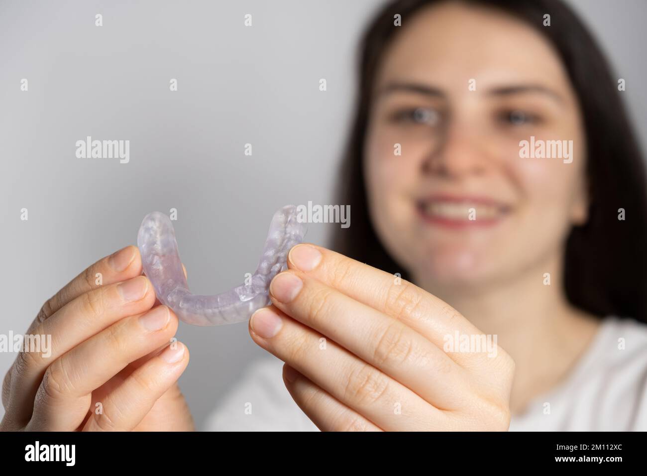 Una donna tiene dentale proteggi bocca, stecca per il trattamento della disfunzione delle articolazioni temporomandibolari, bruxismo, malocclusione, per rilassare i muscoli Foto Stock