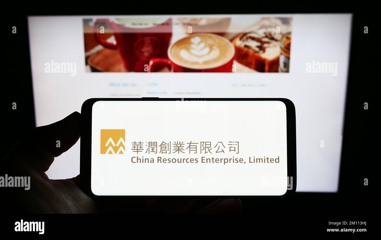 Persona che tiene un telefono cellulare con il logo della società China Resources Enterprise Limited sullo schermo davanti alla pagina Web. Messa a fuoco sul display del telefono. Foto Stock