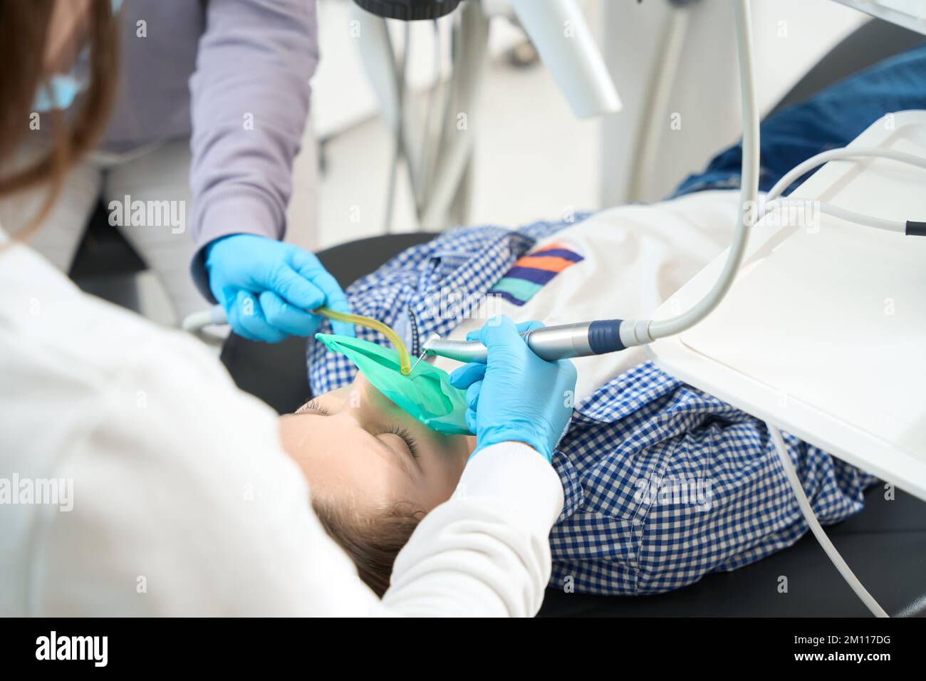 Il medico con assistente in studio dentale sta trattando il dente adolescente Foto Stock