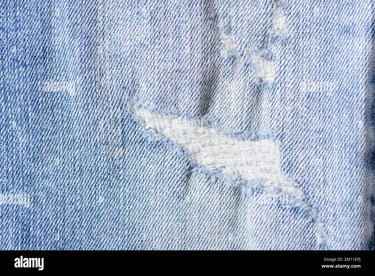 Primo piano di un colore blu e strappato jeans texture sfondo. Foto Stock
