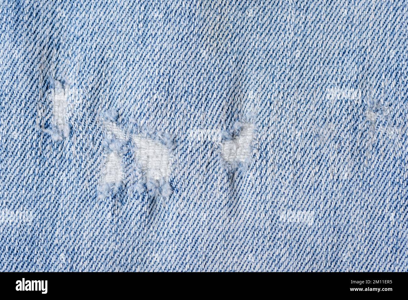Primo piano di un colore blu e strappato jeans texture sfondo. Foto Stock