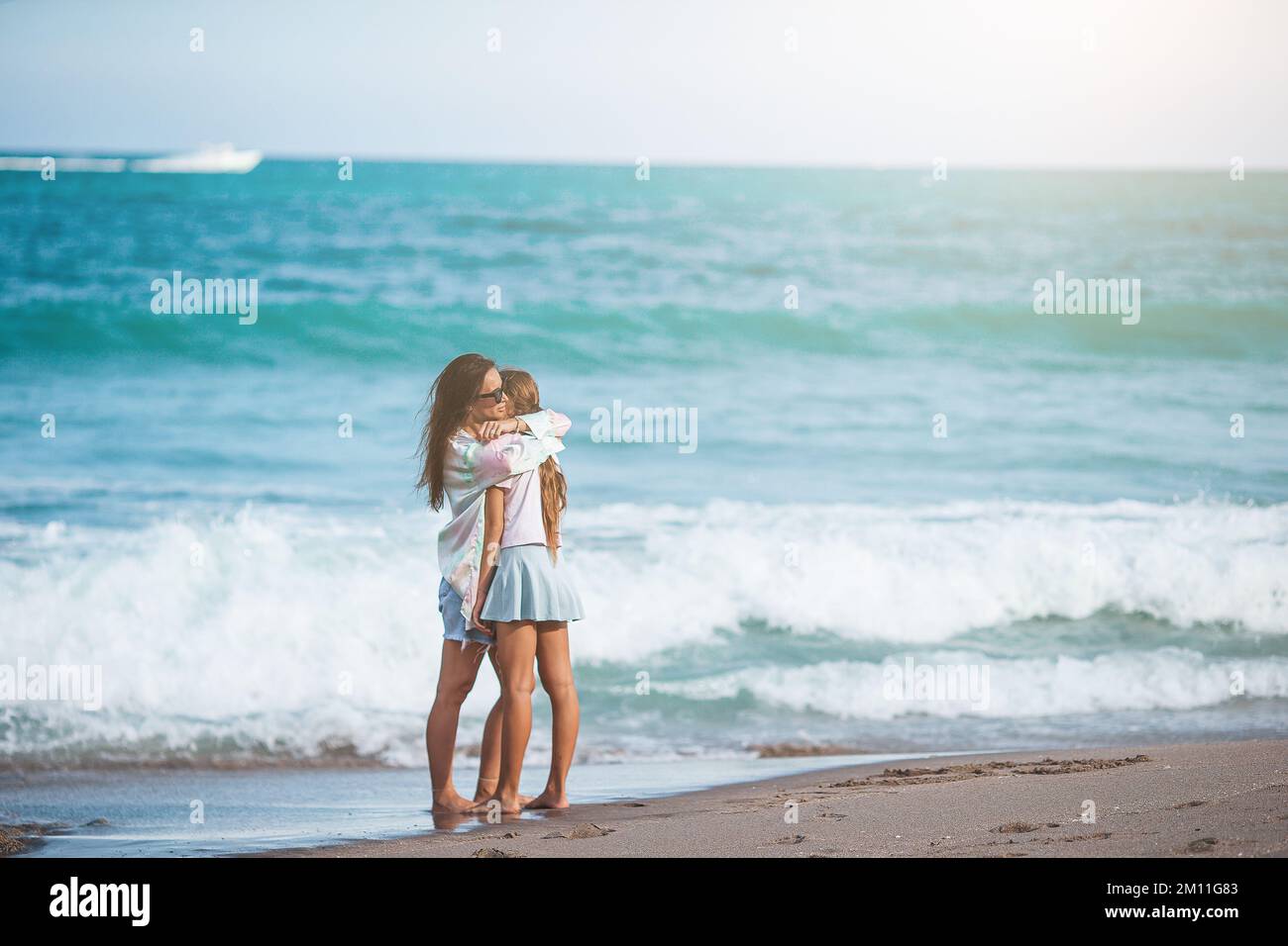 Adorabile bambina e giovane madre sulla spiaggia tropicale bianca Foto Stock