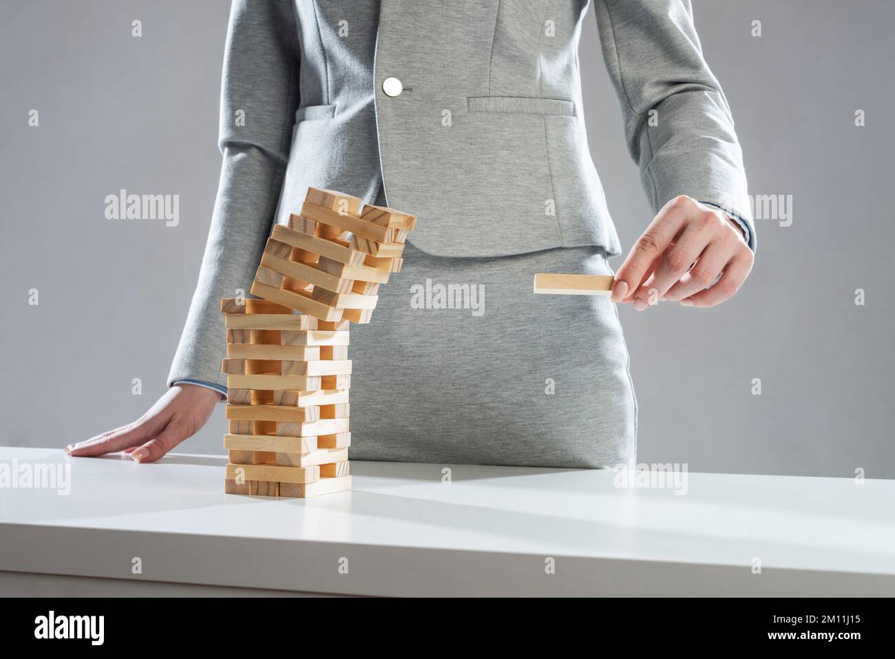 Uomo d'affari che rimuove il blocco di legno dalla torre Foto Stock