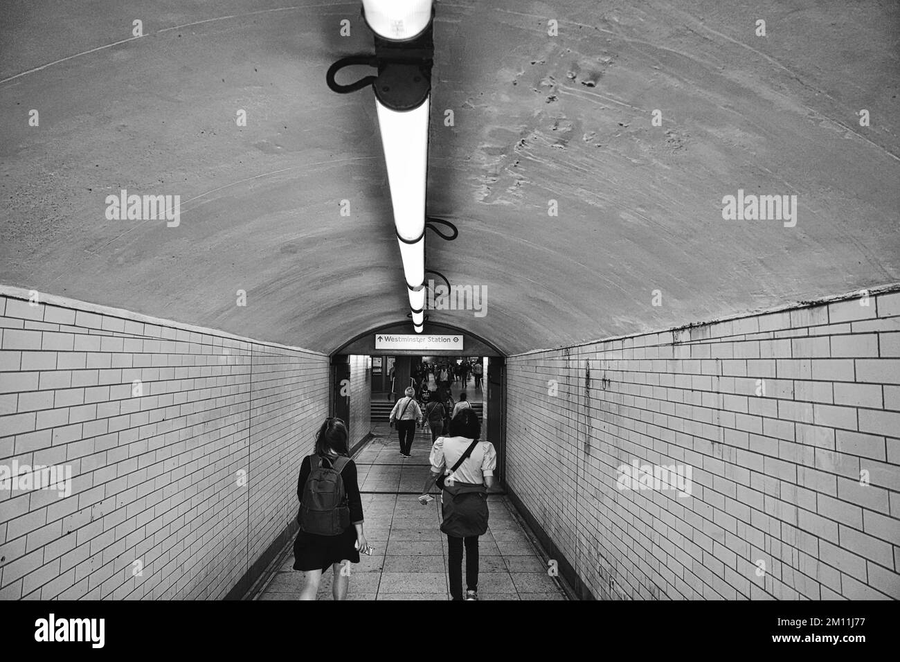 Una vista in scala di grigi delle persone che camminano attraverso il tunnel Foto Stock