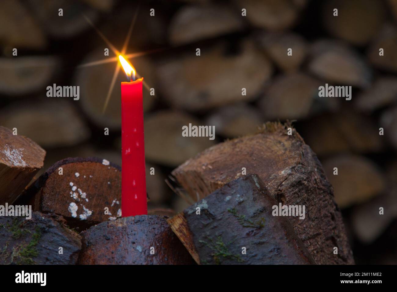 Lume di candela con una stella luminosa in una pila di legno, l'insolito motivo di Natale per la silvicoltura. Foto Stock