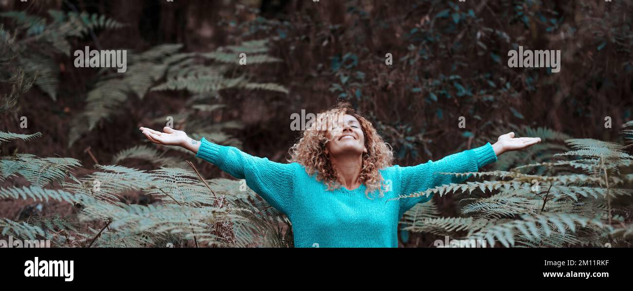 Una giovane donna felice e libera che apre le braccia stretching con gioia e felicità nel parco naturale all'aperto in attività di svago. Concetto di felicità e soddisfazione. Ambiente persone Foto Stock