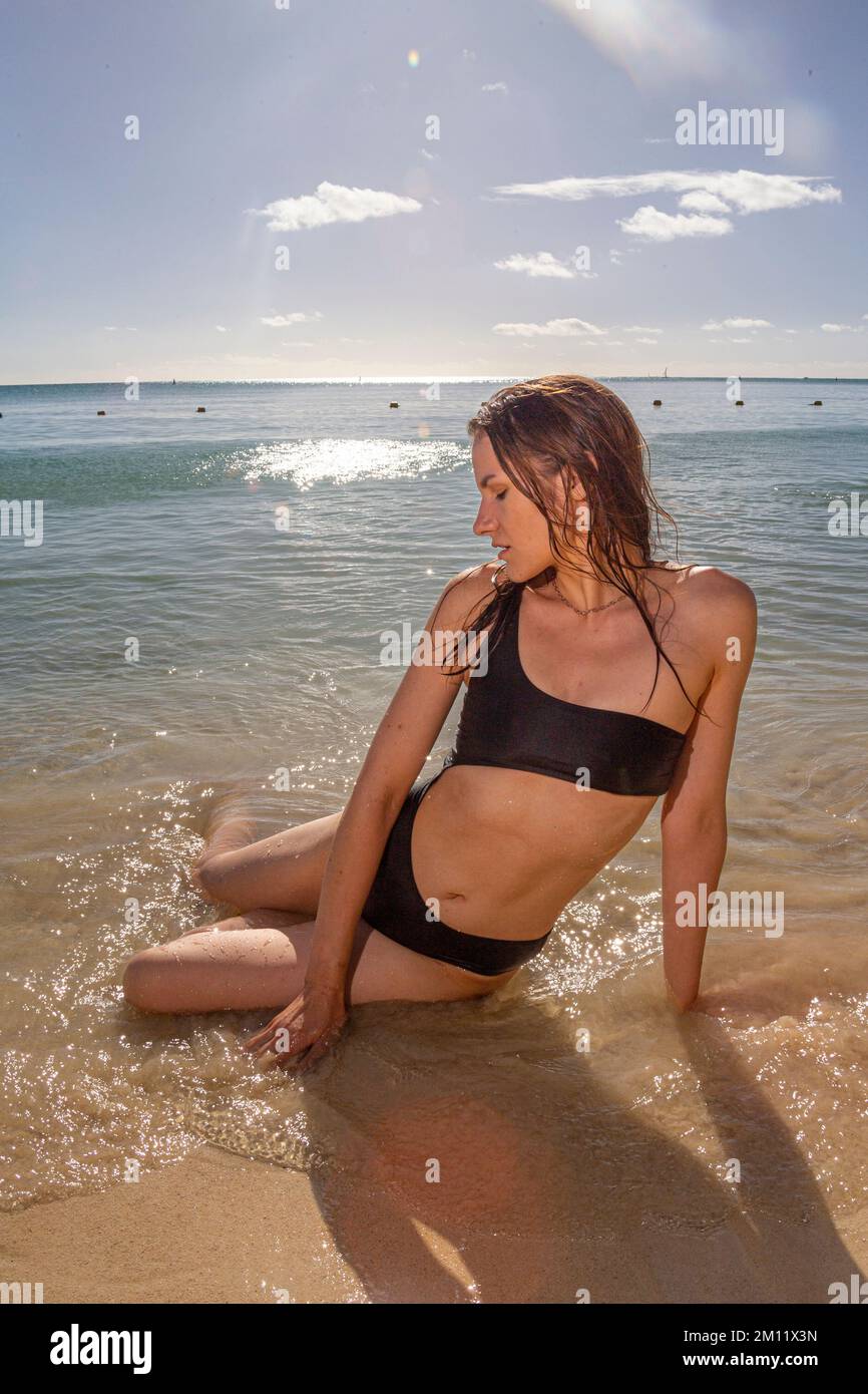 Giovane modella femminile in costume da bagno sexy che posa su una delle spiagge dell'isola Mauritius alla luce del tramonto. Capelli ondulati, pelle abbronzata. Atmosfera tropicale estiva. Foto Stock