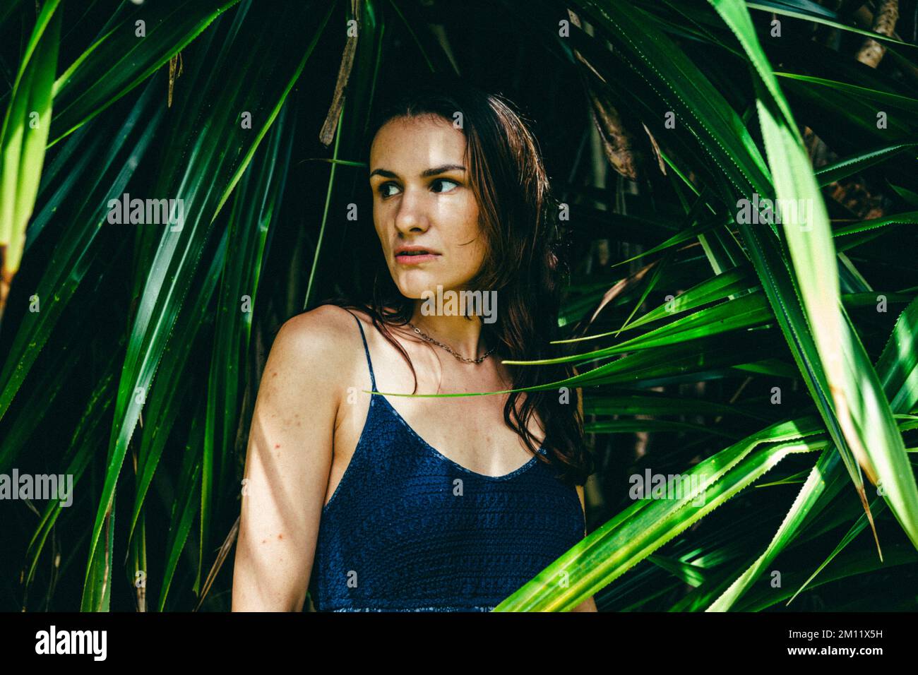 Giovane modello femminile circondato da sfondo naturale da foglie di palma Foto Stock