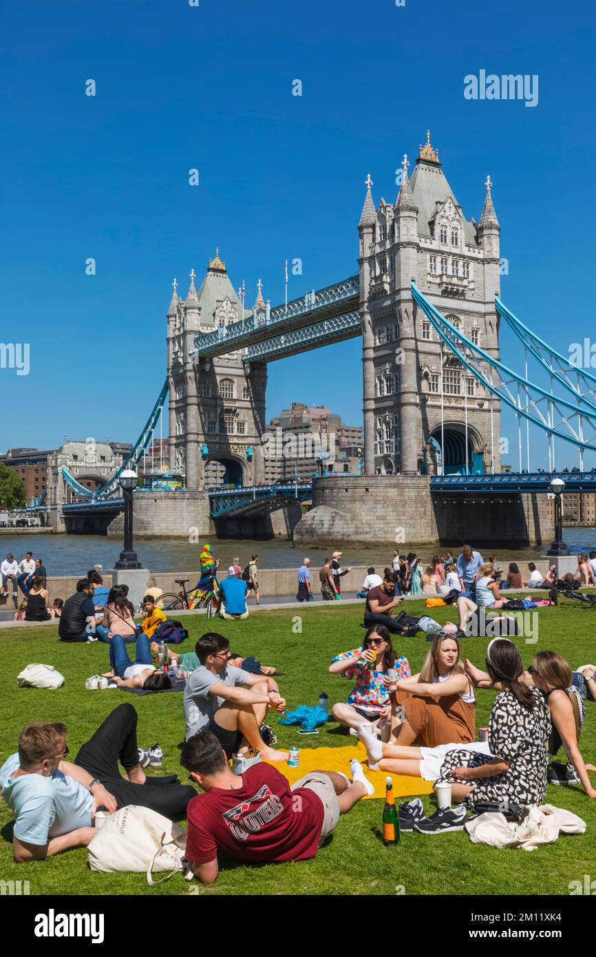 Tower Bridge con persone che si rilassano a Grass a Foreground, Londra, Inghilterra Foto Stock