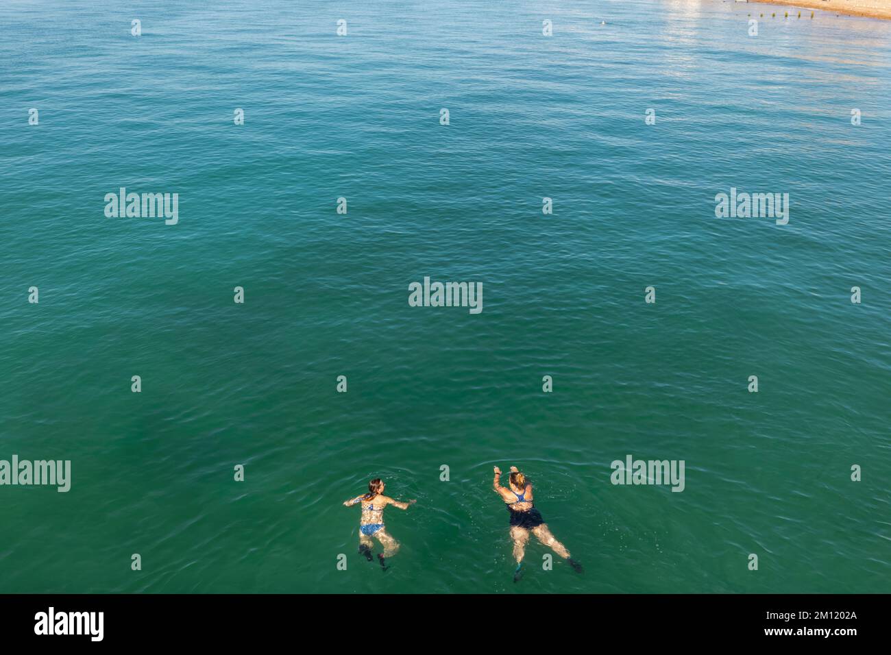 Inghilterra, Sussex occidentale, Worthing, due donne che nuotano nel mare e sulla spiaggia Foto Stock