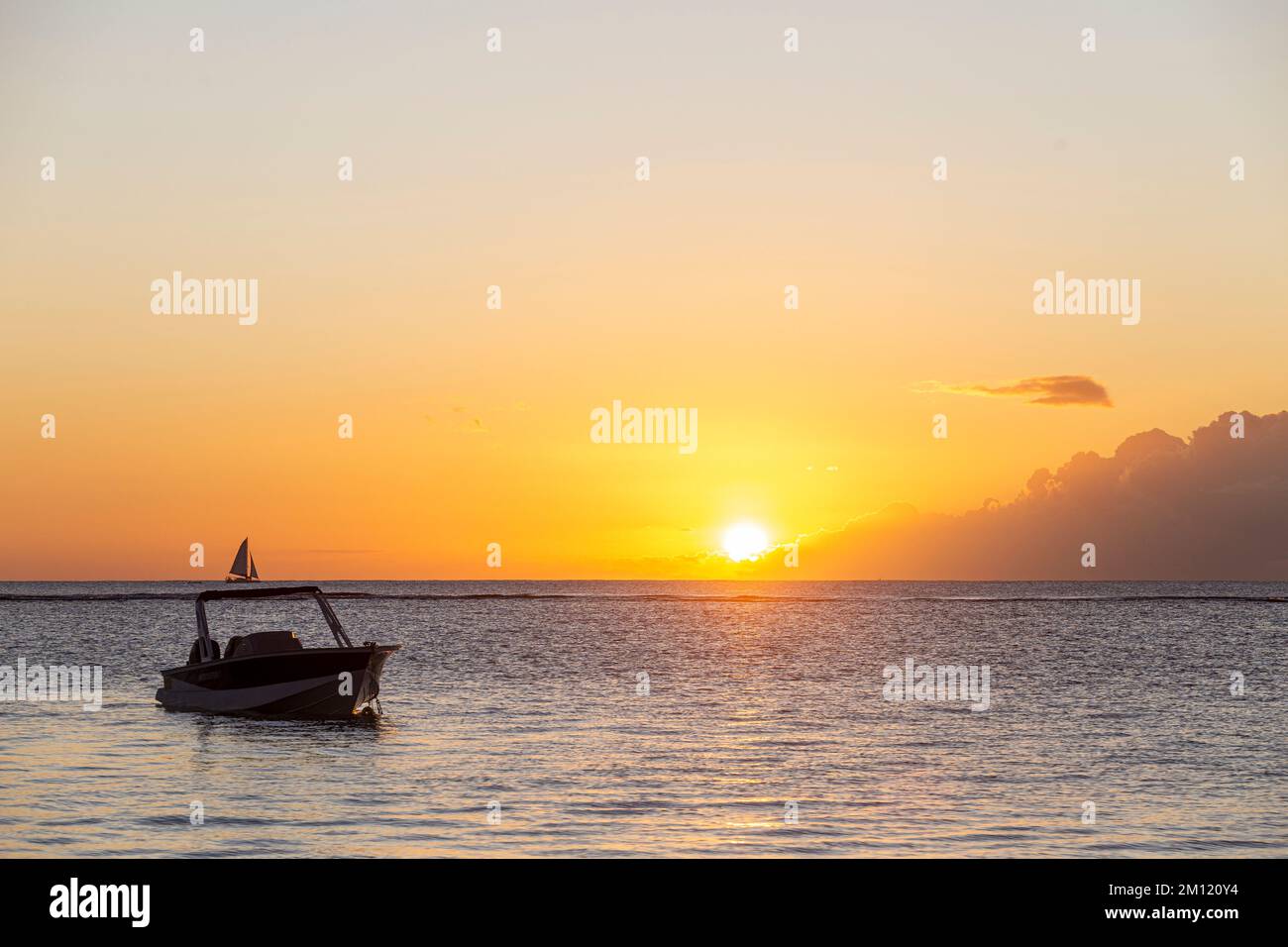 Una barca solitaria nell'oceano - all'orizzonte il tramonto dell'Isola Mauritius, Africa - copyspace Foto Stock